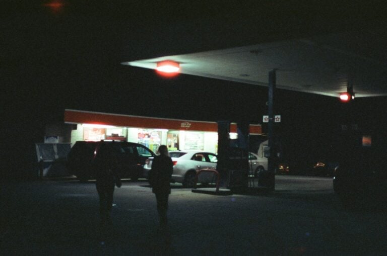 people and cars at the gas station during night