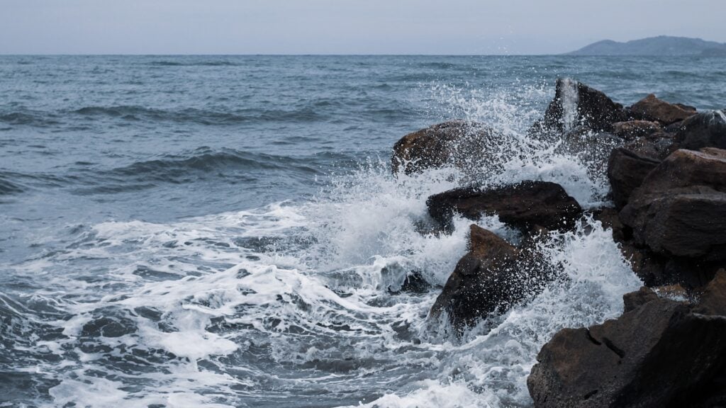 ocean waves crashing on brown rock formation during daytime