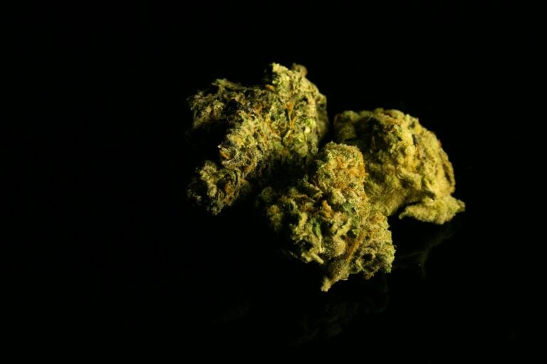 a close up of two marijuana buds on a black surface