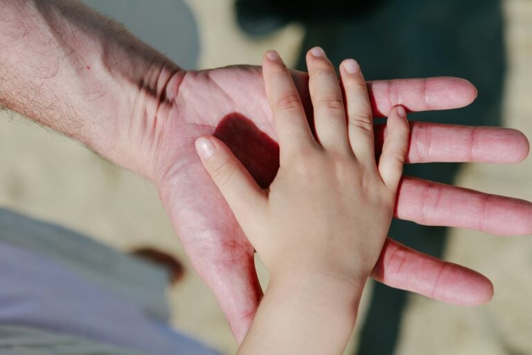 A child's hand rests on an adult's palm.