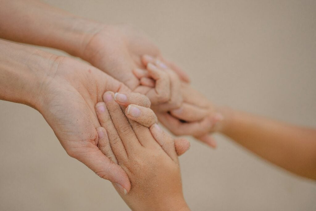 Adult and child hands gently holding each other.