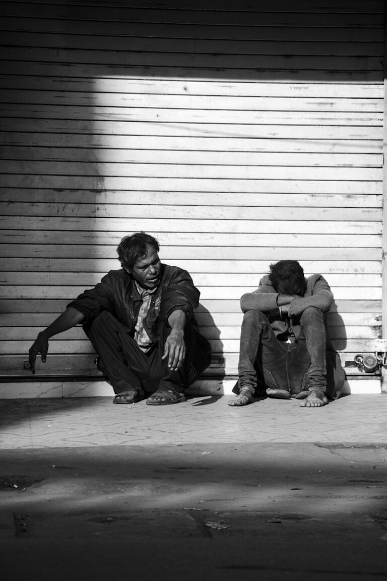 A couple of people sitting on top of a sidewalk